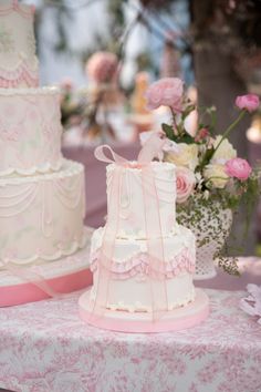 three tiered wedding cakes sitting on top of a table next to pink and white flowers