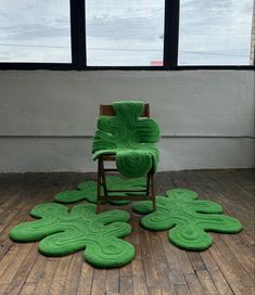 a green chair sitting on top of a hard wood floor next to a large window