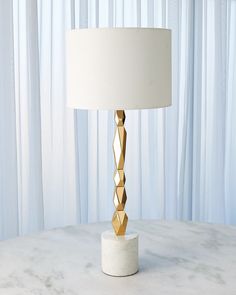 a white table with a gold lamp on it