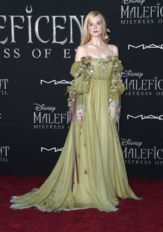 the actress in an off - shoulder gown poses on the red carpet at the maleficent