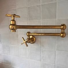 two brass faucets on the wall in a bathroom