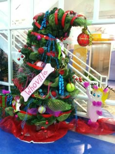 a christmas tree decorated with ornaments and ribbons is on display at the entrance to an office building