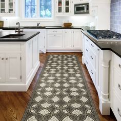 a kitchen with white cabinets, black counter tops and an area rug on the floor