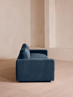 a blue couch sitting on top of a hard wood floor next to a white wall