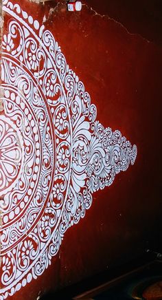 an intricately designed piece of art on the side of a red wall with white paint