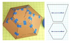 an origami hexagonal object with blue tape on it and another piece of construction paper