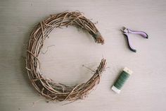 a wreath with some scissors next to it on a wooden table and another piece of wire