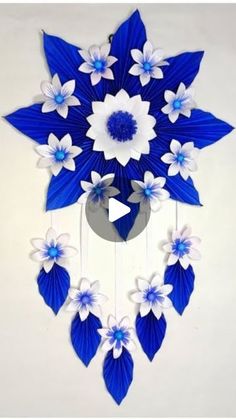 a blue and white clock with flowers hanging from it's sides, on a wall