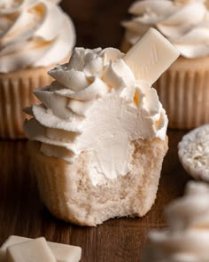 cupcakes with white frosting and marshmallows on a wooden table