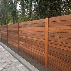 a wooden fence next to a brick walkway