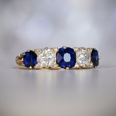 three stone ring with blue and white stones on the sides, set in yellow gold