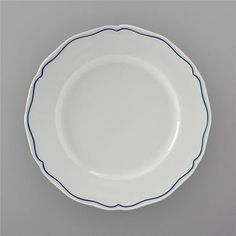 an empty white plate with blue lines on the rim, against a gray wall background