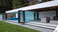 an outdoor living area with glass walls and sliding doors on the outside, surrounded by lush green grass