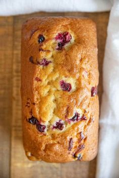 a loaf of blueberry bread sitting on top of a wooden cutting board