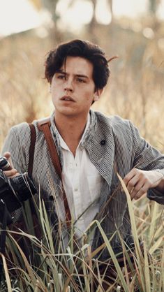 a man sitting in tall grass holding a camera