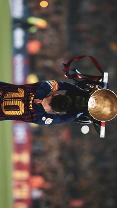 a man holding a trophy on top of a field