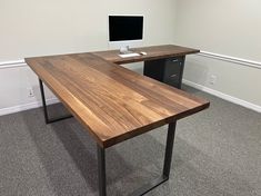 a desk with a computer on it in an empty office space next to a wall