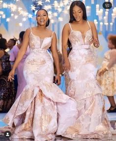 two women in dresses walking down the runway