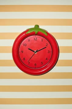 a red clock hanging from the side of a wall with stripes on it's walls