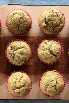 twelve muffins in pink paper lined up on a cutting board