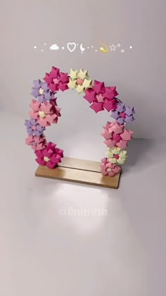 an origami star wreath is displayed on a wooden stand with the word love written below it