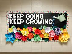 a sign that says keep going, keep growing with flowers in front of it on the wall