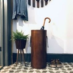 an umbrella and some shoes in front of a wall mounted coat rack with hooks on it