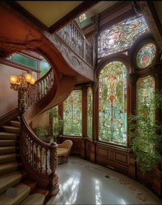 an ornate staircase with stained glass windows next to a potted plant in the corner