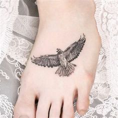 a bird tattoo on the foot of a woman