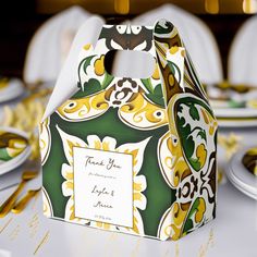 a green and yellow patterned treat bag sitting on top of a table with white plates