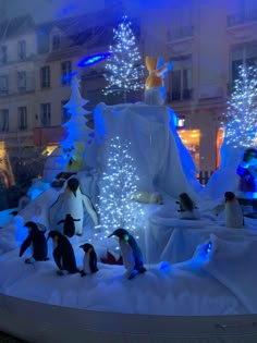 penguins are standing in the snow with christmas lights