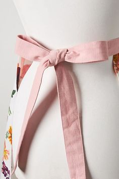 a woman wearing a pink belt with flowers on the front and side, tied around her waist