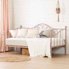 a white day bed with pink curtains and pillows