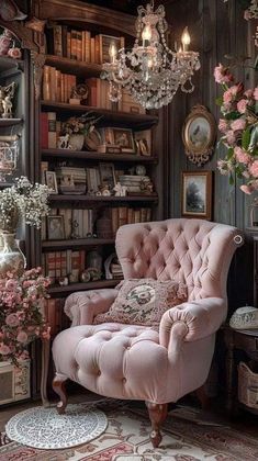 a pink chair sitting in front of a book shelf filled with books