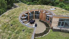 an aerial view of a circular house with green roof and grass on the top floor