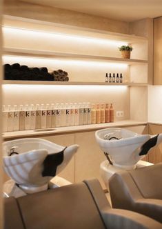 two white bowls sitting on top of a counter in a room with shelves filled with bottles