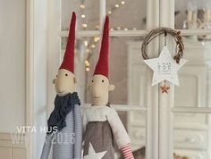 two dolls are sitting next to each other in front of a christmas wreath and window