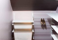 a closet with white shelves and clear plastic bins on the bottom shelf next to two pairs of high heeled shoes