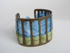 This cuff bracelet is in blue and green hand painted silk and bronze colored metal * bronze and silk colored metal * width 5 cm * 17 cm in length * High quality French paintings *Heat fixed to preserve colors * Made in Lyon * blue, chartreuse green, bronze * bohemian It's the perfect useful gift to give to please Mother's Day, Wedding Anniversary, Birthdays Sending : beautifully packaged in an organza bag and in a black gift box sent by colissimo to France My store: https://www.etsy.com/fr/shop/ French Paintings, Green Bracelet, Chartreuse Green, Green Hand, Painted Silk, Jewelry Blue, Hand Painted Silk, Black Gift Boxes, Black Gift