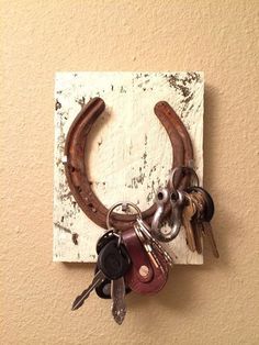 a bunch of keys hanging from a hook on the side of a wall with a horse shoe