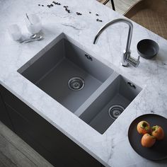 a kitchen sink with two oranges on the counter