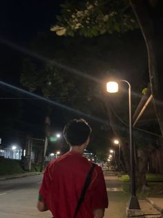 a man is walking down the street at night with his back turned to the camera