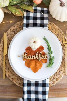 a white plate topped with an autumn leaf and the word thank you written on it