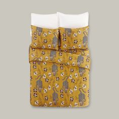 a yellow comforter with monkeys and flowers on the bottom, along with two pillows