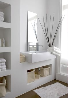 a white bathroom with shelves and towels on the shelf next to the sink is shown