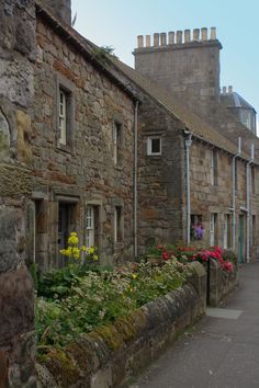 an old stone building with flowers growing out of it