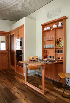 a kitchen with wooden floors and cabinets in the center, along with a dining room table