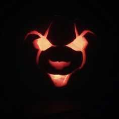 a carved pumpkin in the shape of a devil's head with glowing eyes and fangs