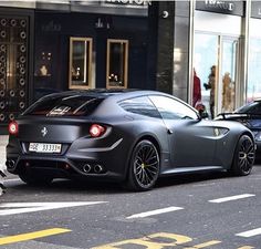 a black sports car is parked on the side of the street in front of a building