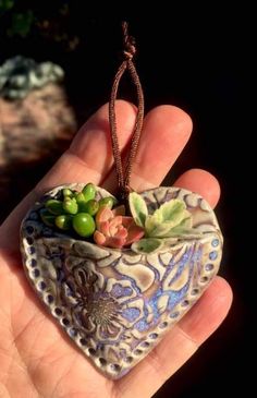 a small heart shaped planter with succulents in it's center